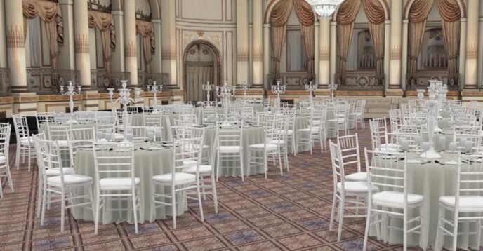 A grand ballroom from The Plaza New York with ornate decor is set up for an event with round tables covered in white tablecloths and white chairs arranged around each table.