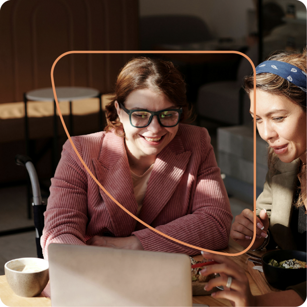 Two planners look at a laptop while they smile; agreeing on the table settings.